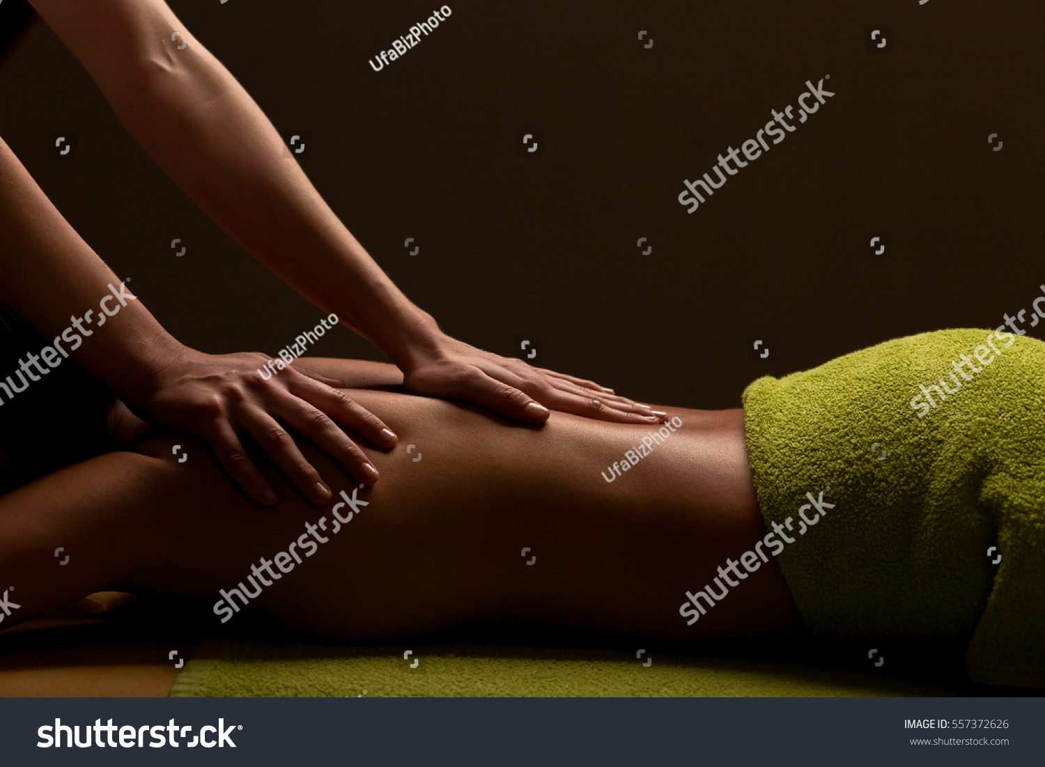 close-up masseur hands doing back massage in spa center. low key photo #557372626