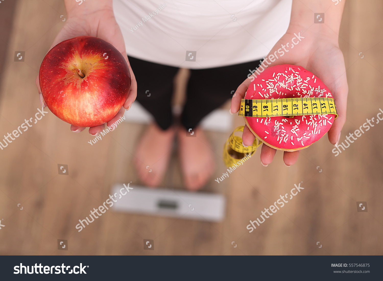 Close up view of woman making choice between apple and donut with blurred scales on background. Dieting concept #557546875