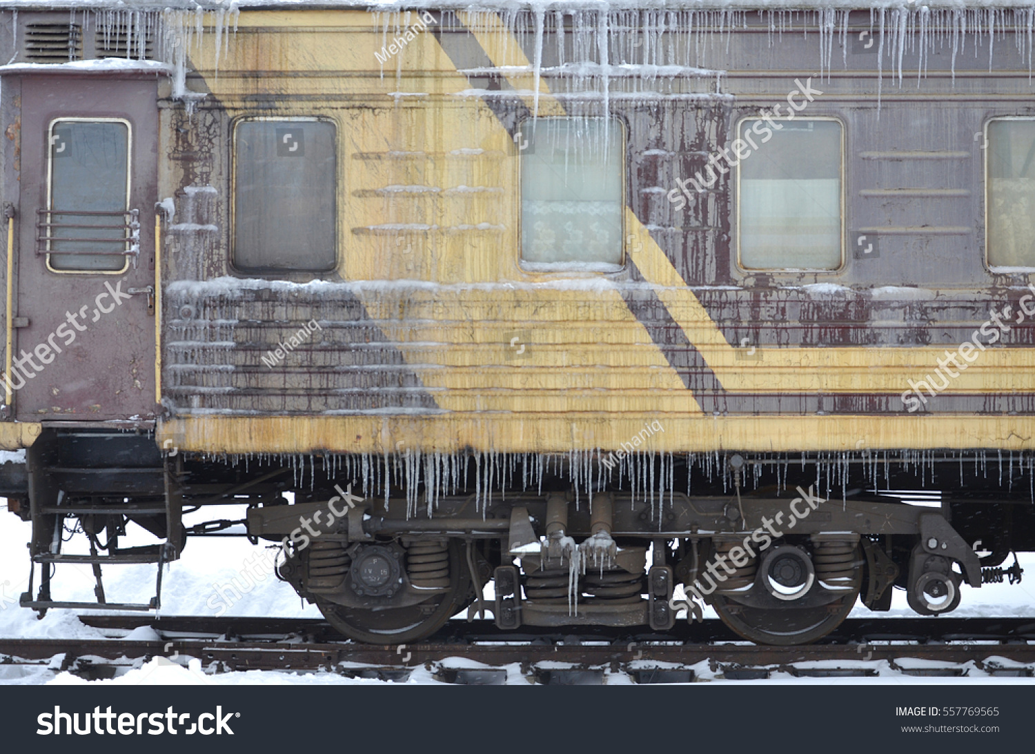 Detailed photo of a frozen car passenger train with icicles and ice on its surface. Railway in the cold winter season #557769565