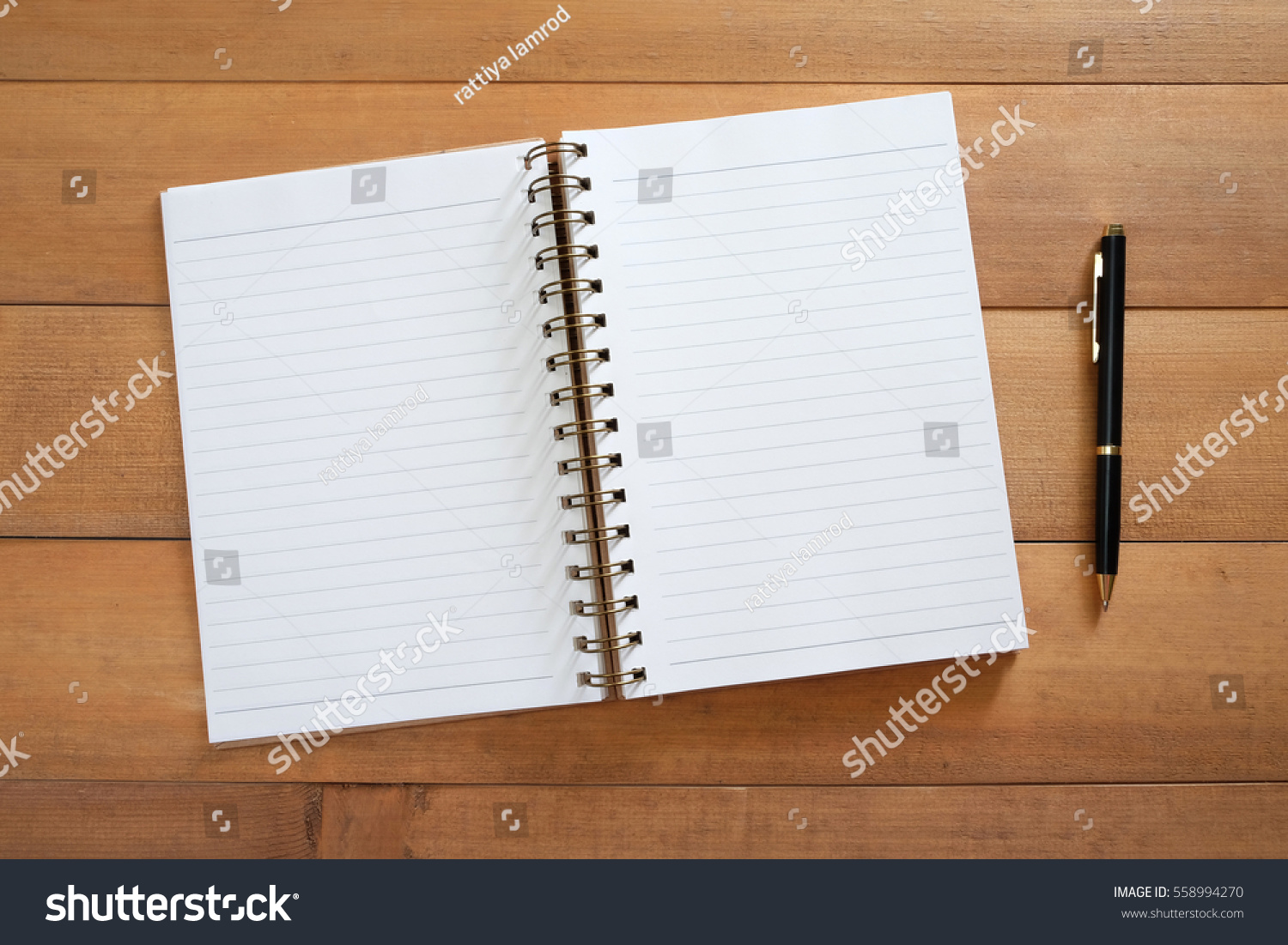 Blank open notebook with pen on wooden desk #558994270