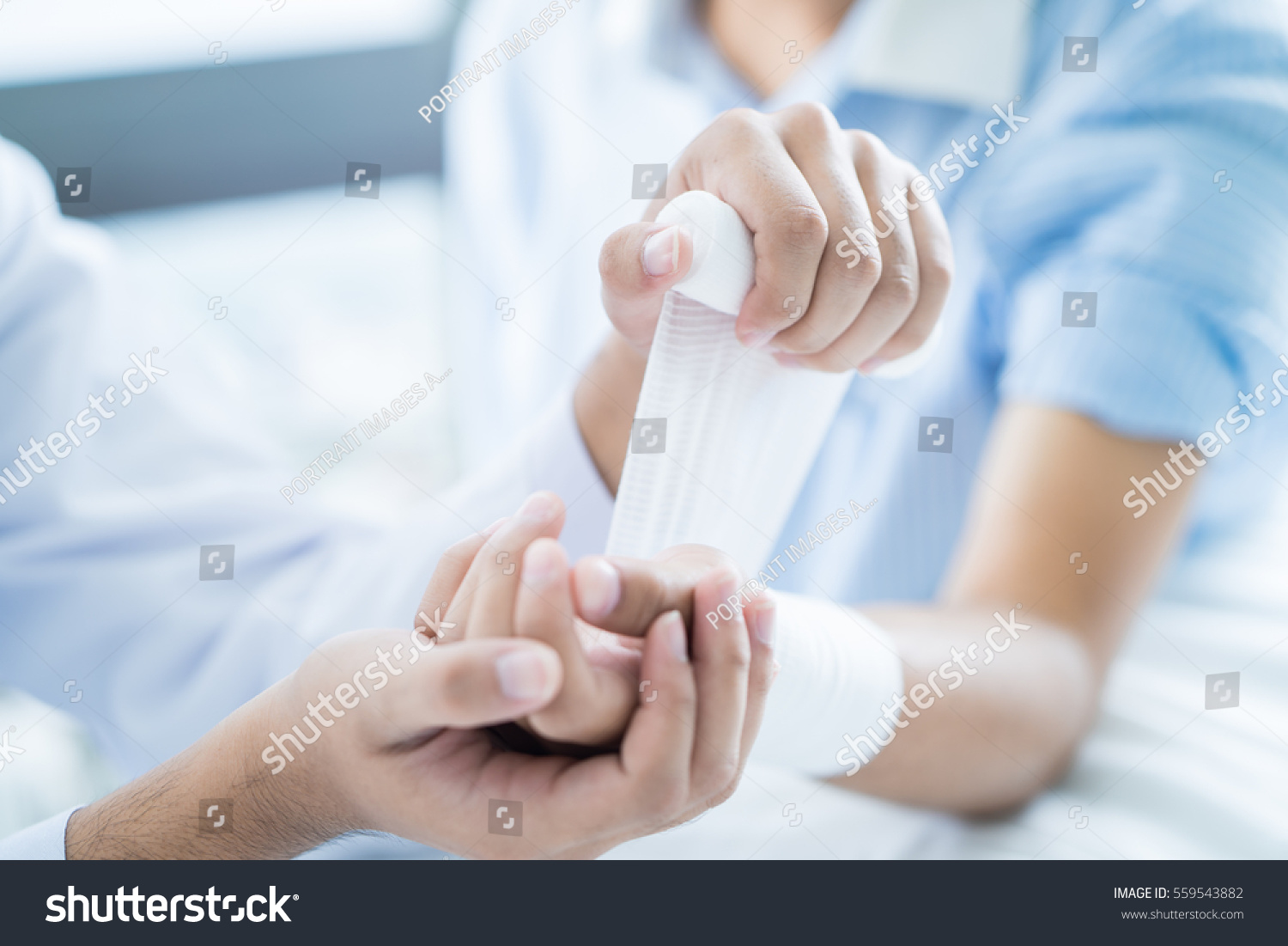 Close-up doctor is bandaging upper limb of patient. #559543882