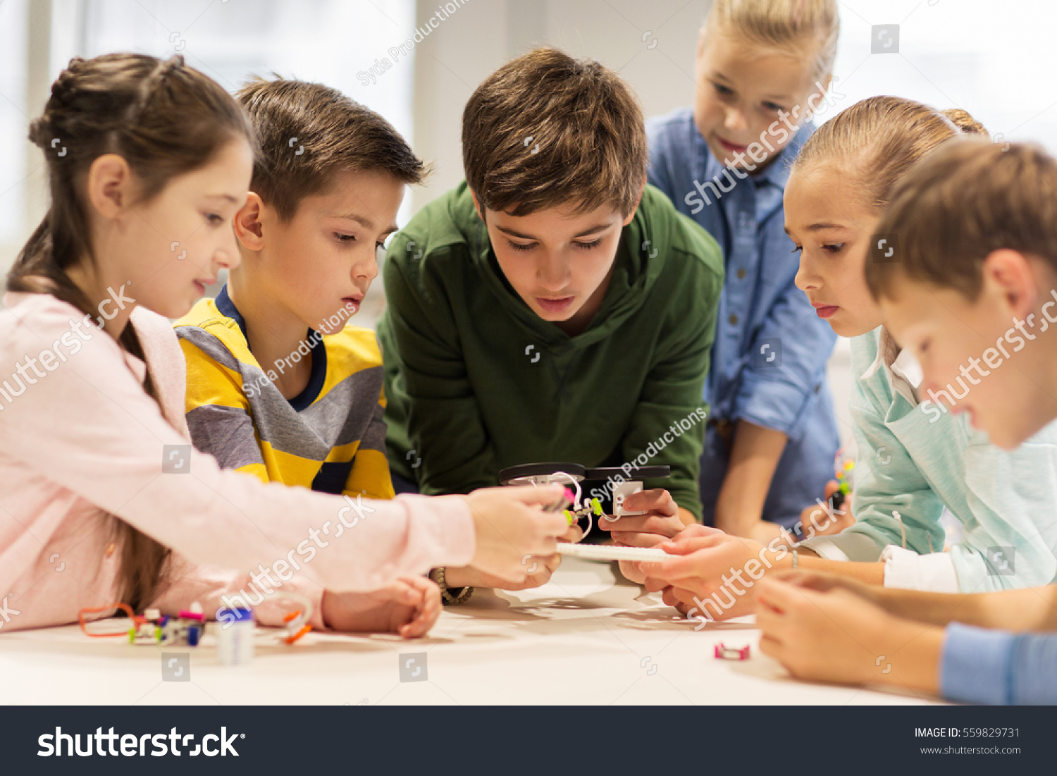 education, children, technology, science and people concept - group of happy kids building robots at robotics school lesson #559829731