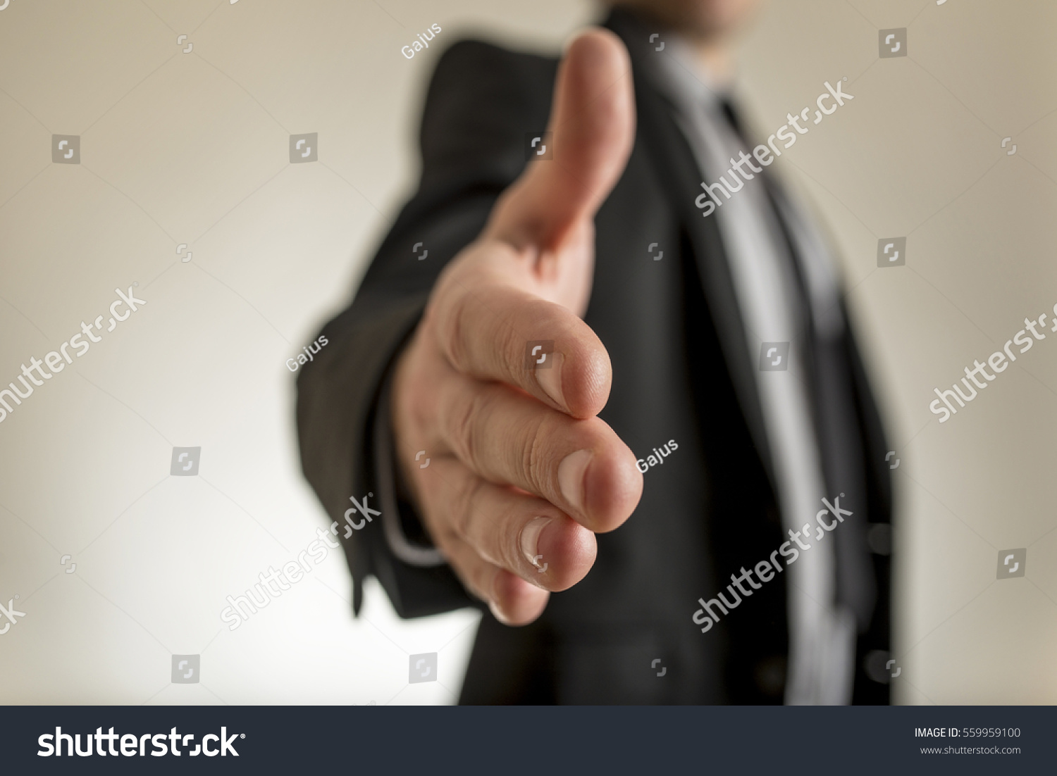 Close-up view of businessman hand reached out to handshake. Incognito man in suit blurred in background. #559959100