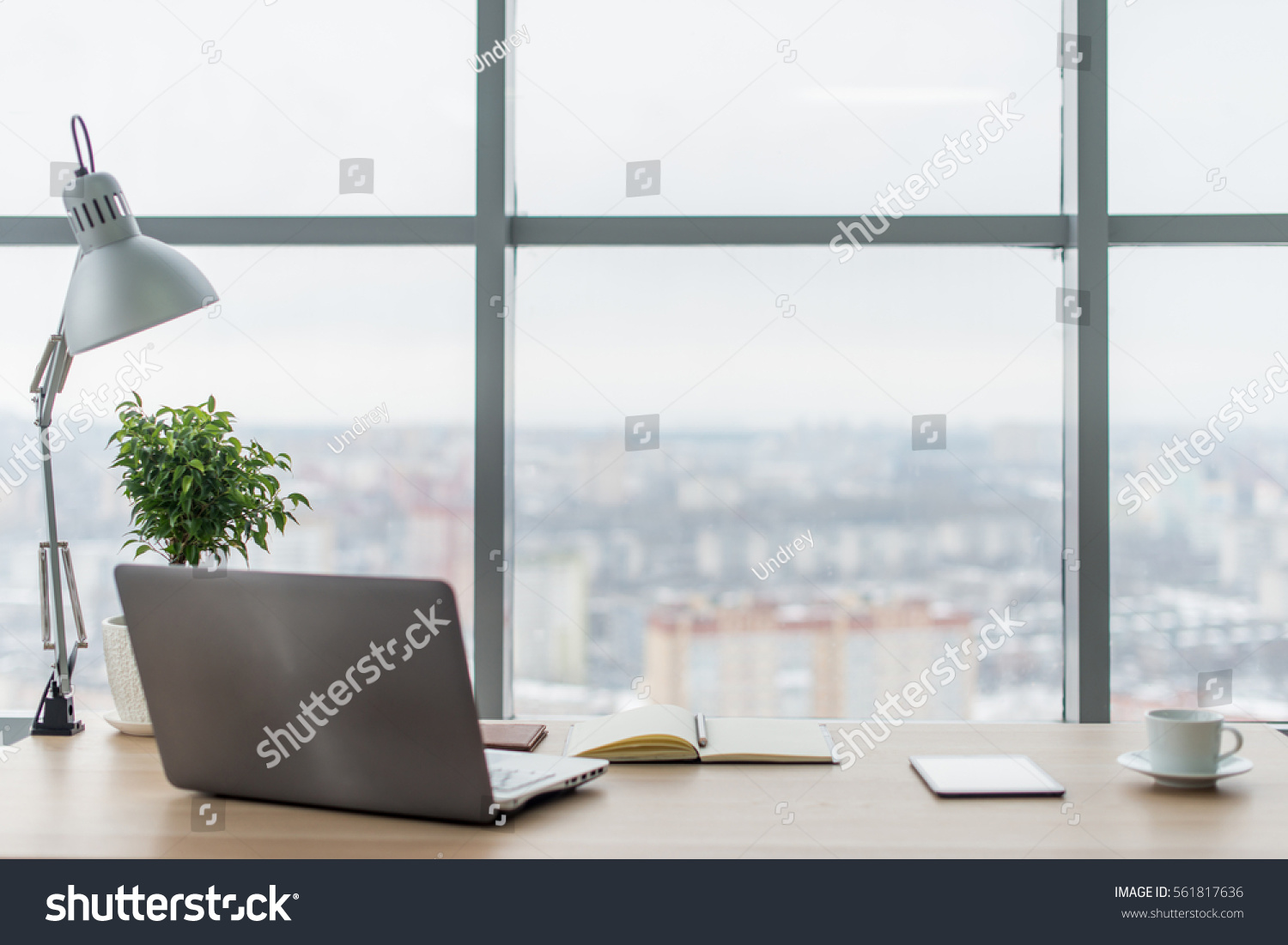 Workplace with notebook laptop Comfortable work table in office windows and city view. #561817636