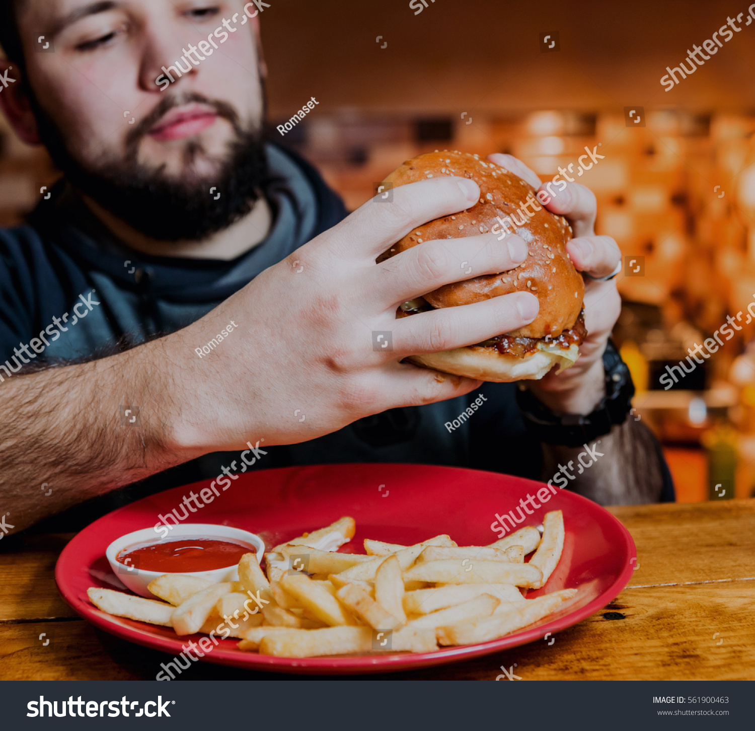Young man eating a cheeseburger. Restaurant #561900463