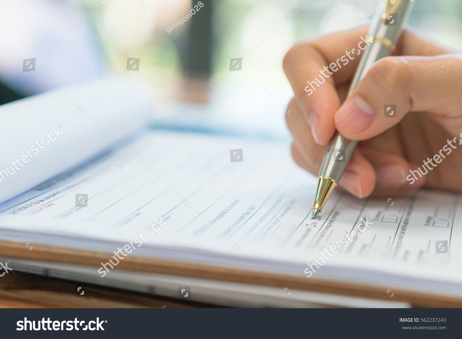 Hand with pen over application form #562237243