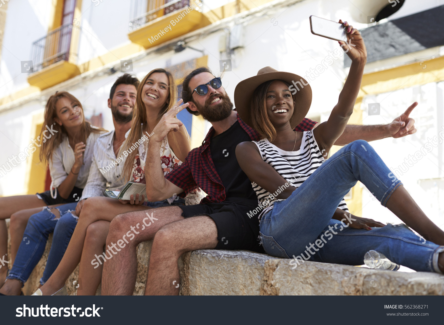Five friends sitting on a wall in Ibiza taking a selfie #562368271