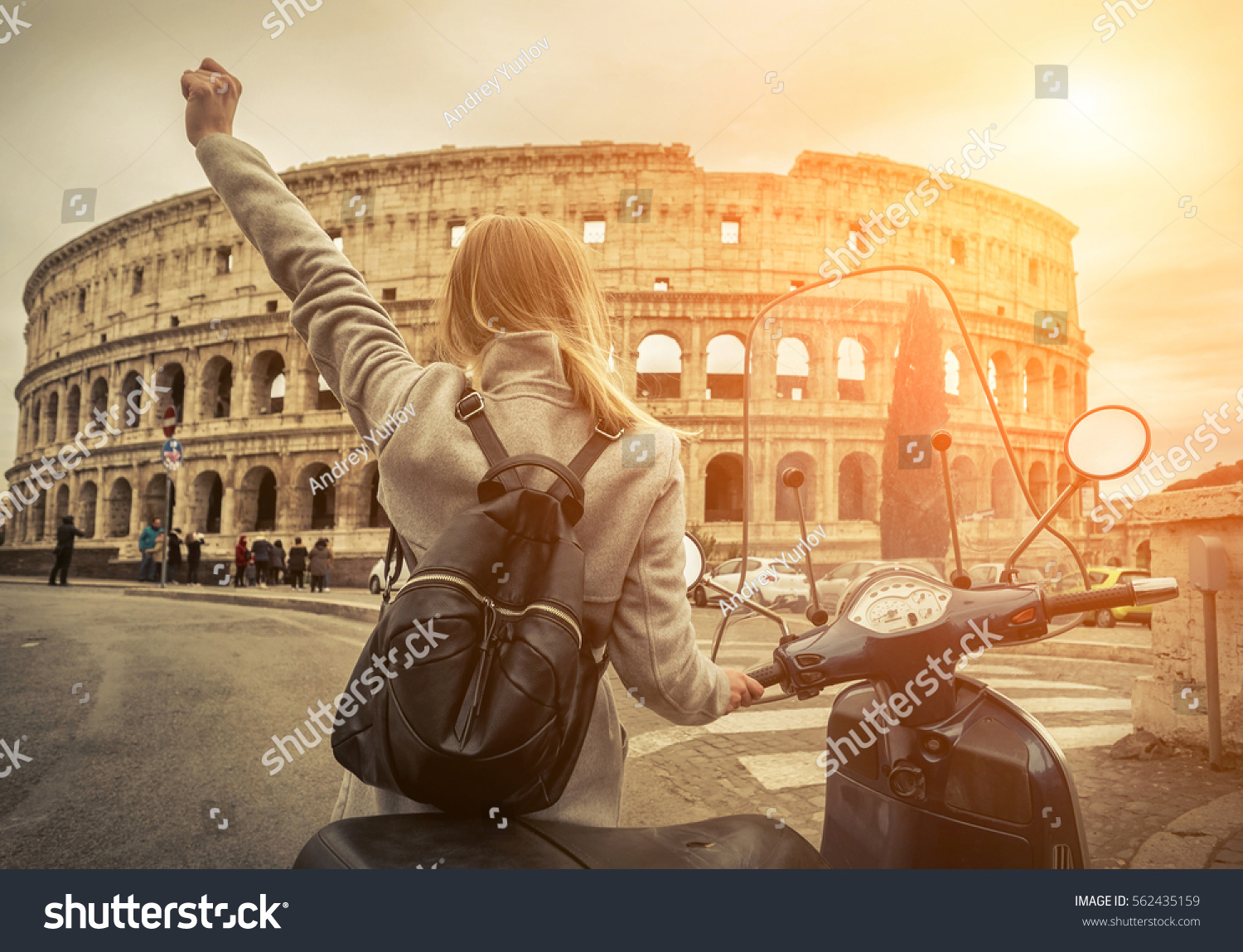 Woman tourist near the Coliseum in Rome under sunlight and blue sky. Famous popular touristic place in the world. #562435159