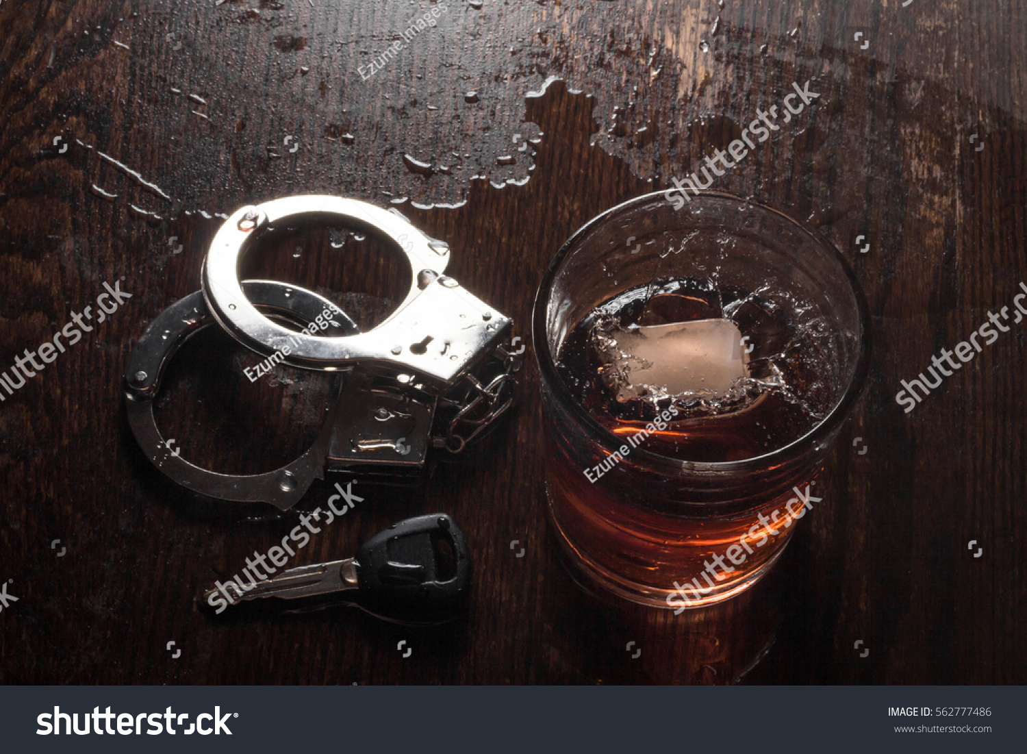 Rocks glass of whisky with handcuffs and keys symbolizing drunk driving arrest #562777486