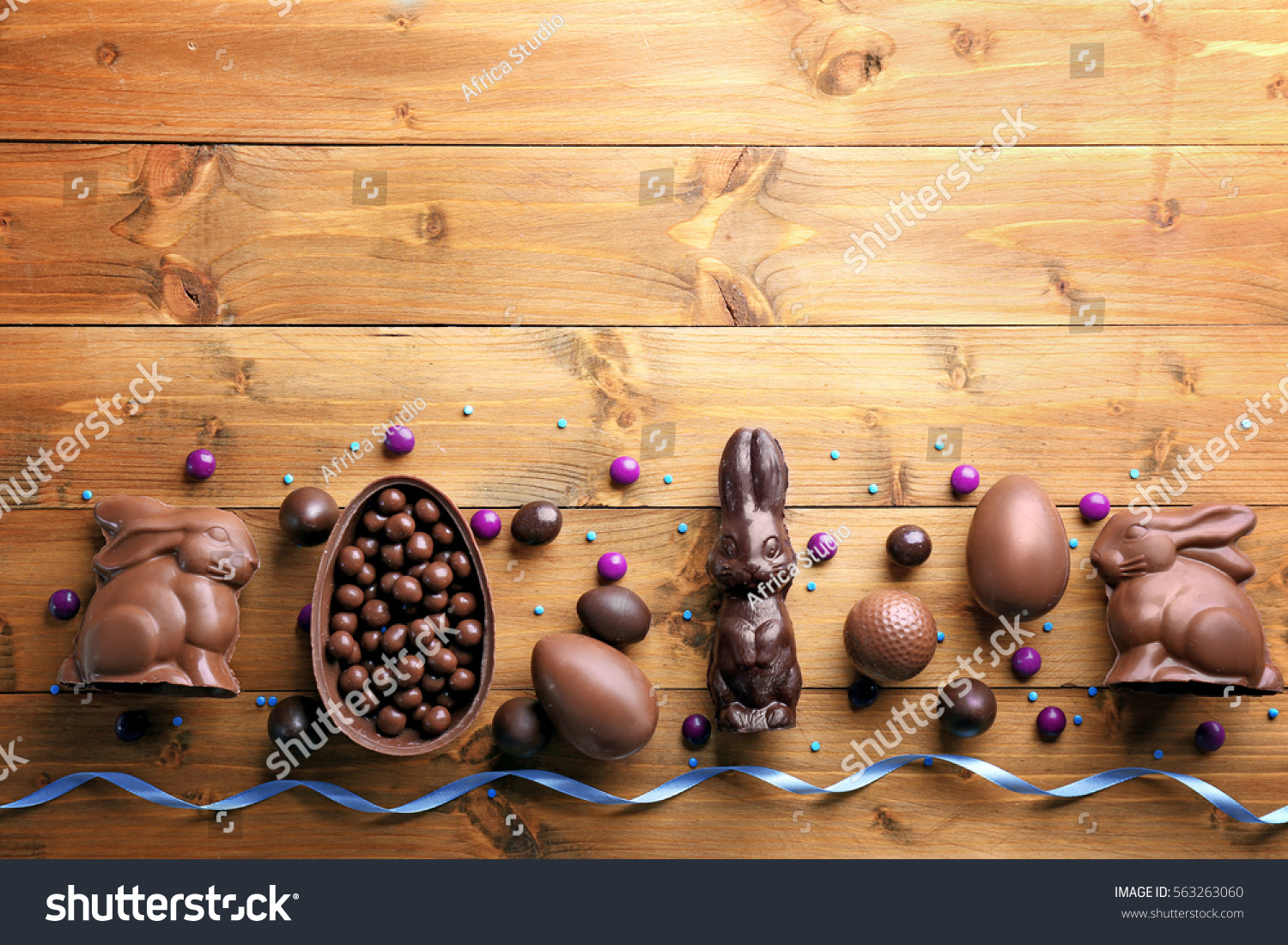 Chocolate Easter eggs, rabbits and sweets on wooden background #563263060