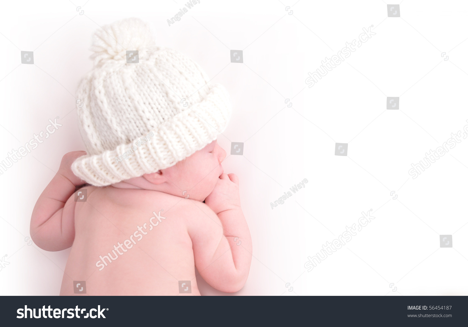 A newborn baby is wearing a white hat and laying down sleeping on a white isolated background. Use the photo to represent life, parenting or childhood. #56454187