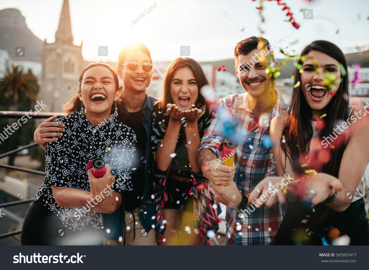 Group of friends enjoying party and throwing confetti. Friends having fun at rooftop party.