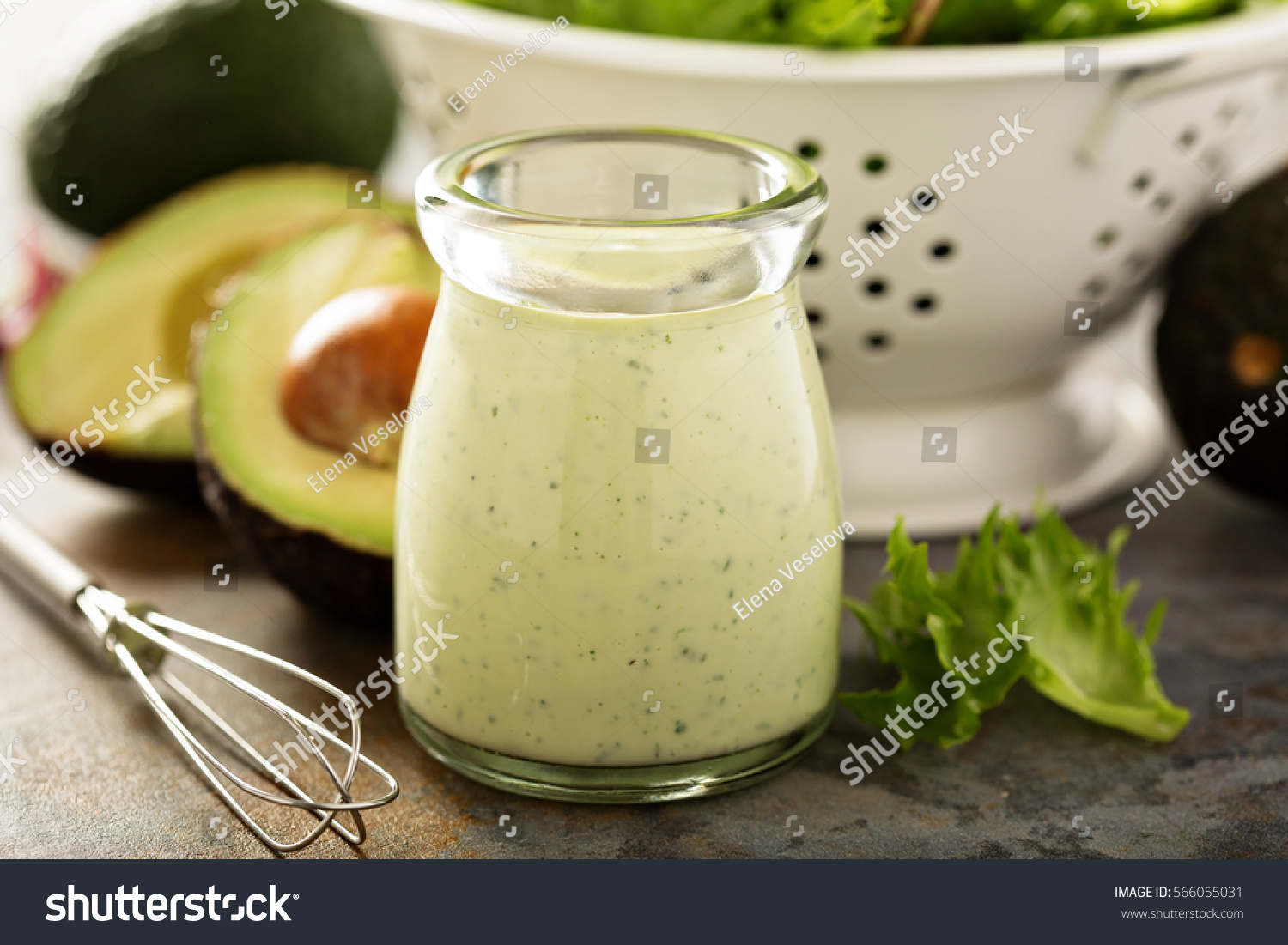 Homemade avocado ranch dressing in a small jar with fresh greens. #566055031