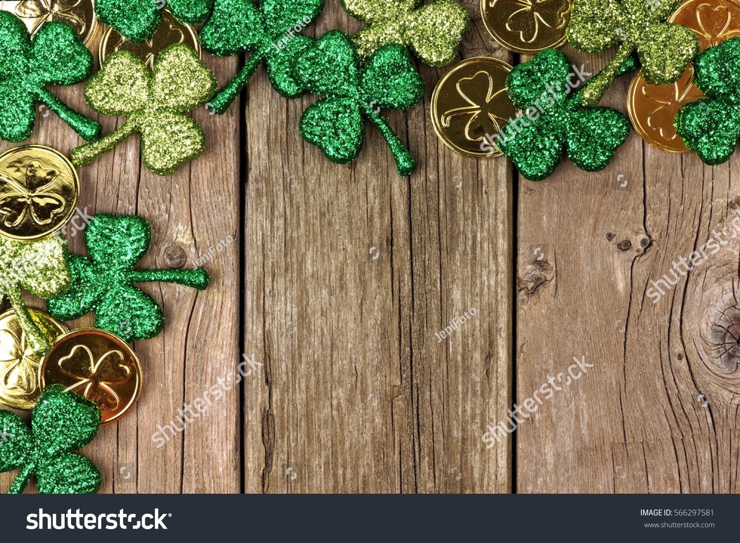St Patricks Day corner border of shamrocks and gold coins over a rustic wood background #566297581