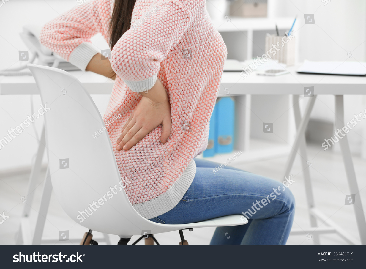 Beautiful young woman suffering from backache in office #566486719