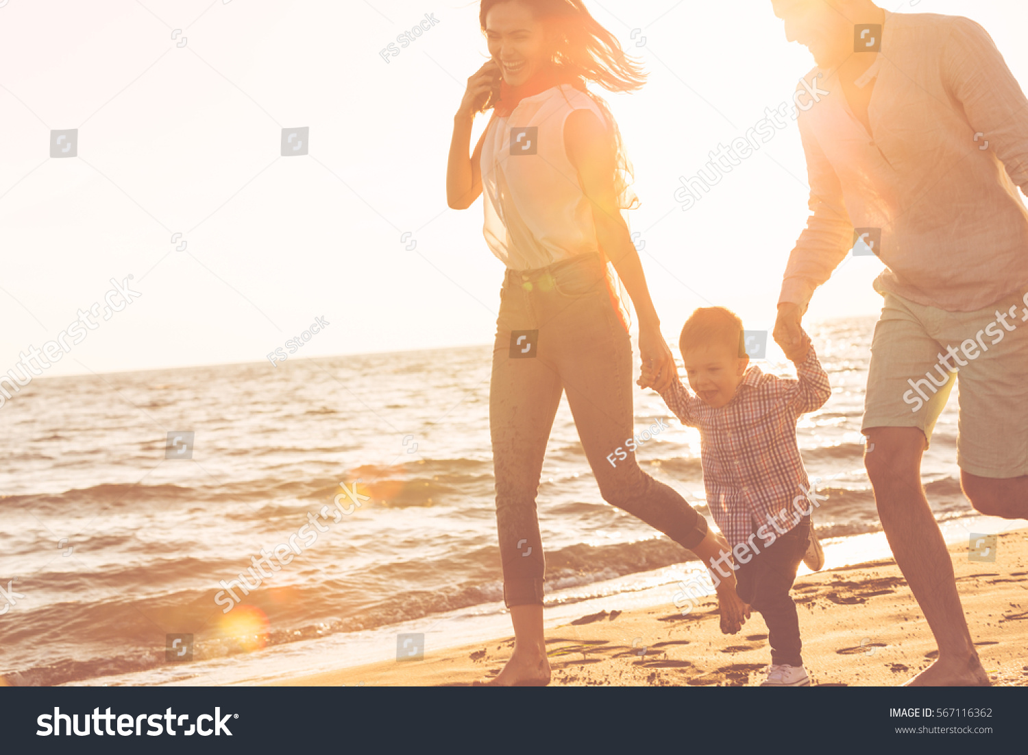 happy young family have fun on beach run and jump at sunset #567116362