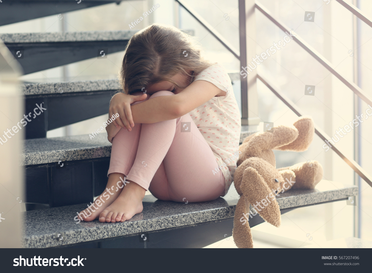 Sad little girl sitting on stairs #567207496