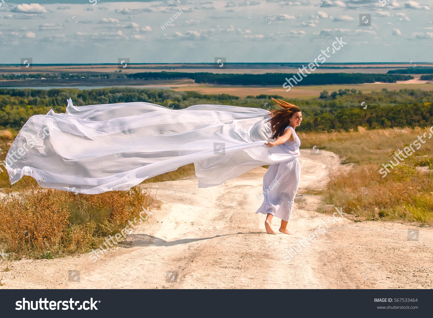 sunny day on the white trail running girl, wind waves a white cloth and long hair #567533464