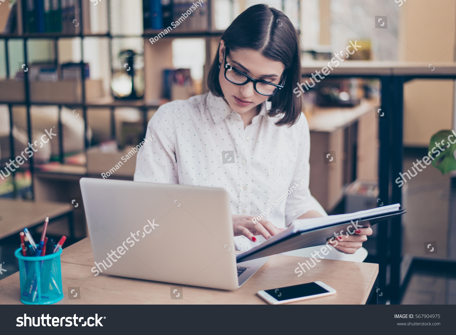 Concentrated smart young  businesswoman using her computer in office. #567904975