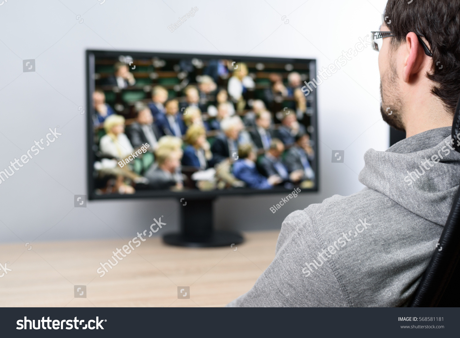 relaxed man watching (on TV) parliament during vote on laws #568581181