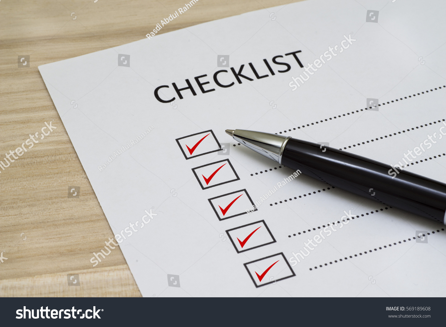 Checklist concept - checklist box with red checkmark, paper and a pen with checklist word on wooden table #569189608