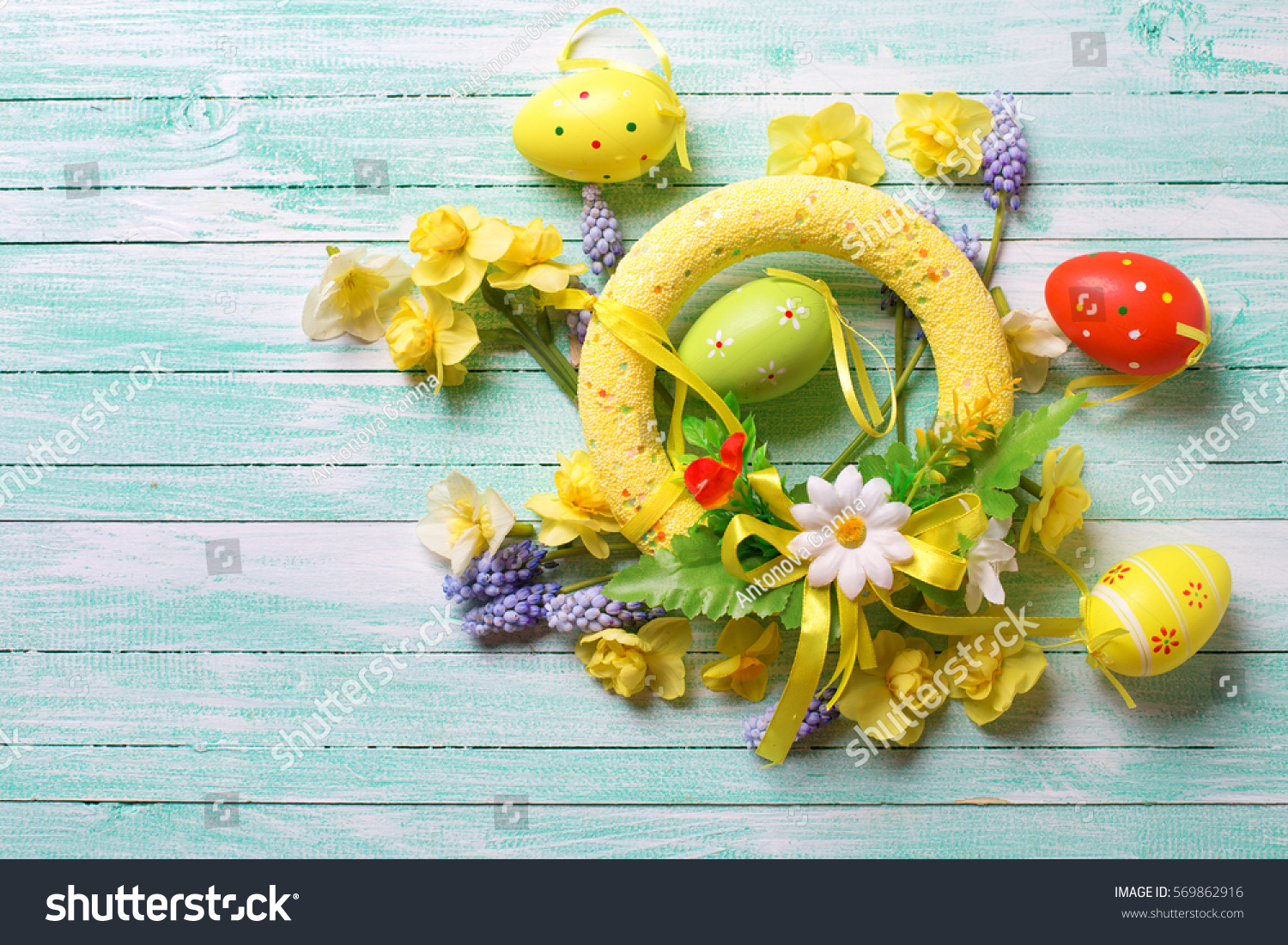  Easter background for design. Decorative Easter wreath and eggs,   bright spring flowers on turquoise wooden background.Selective focus. Place for text.  #569862916