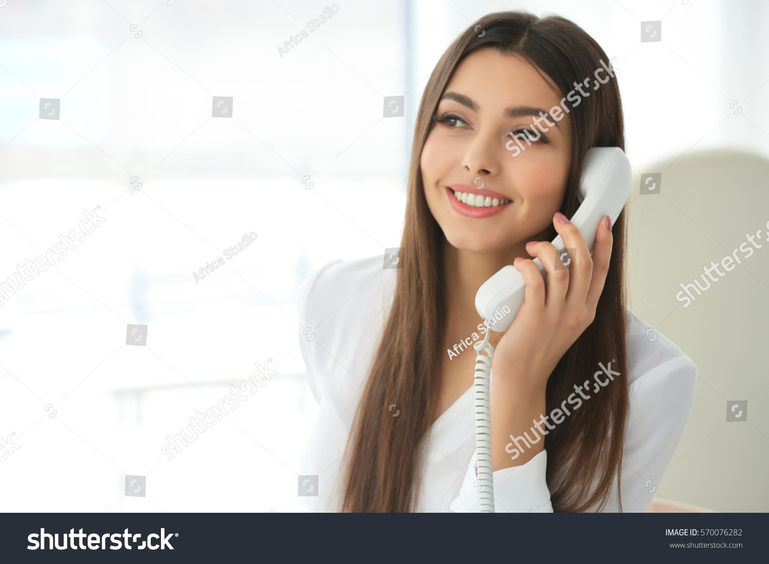 Beautiful young woman talking by telephone in office #570076282