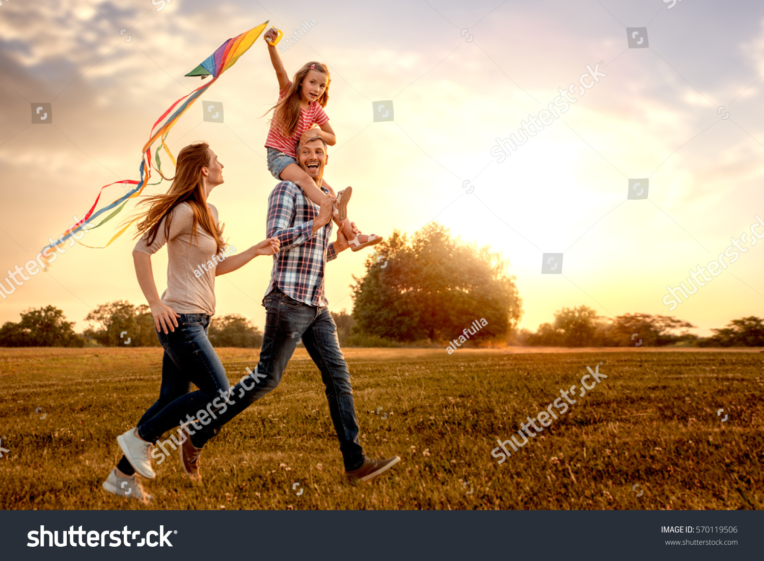 family running through field letting kite fly