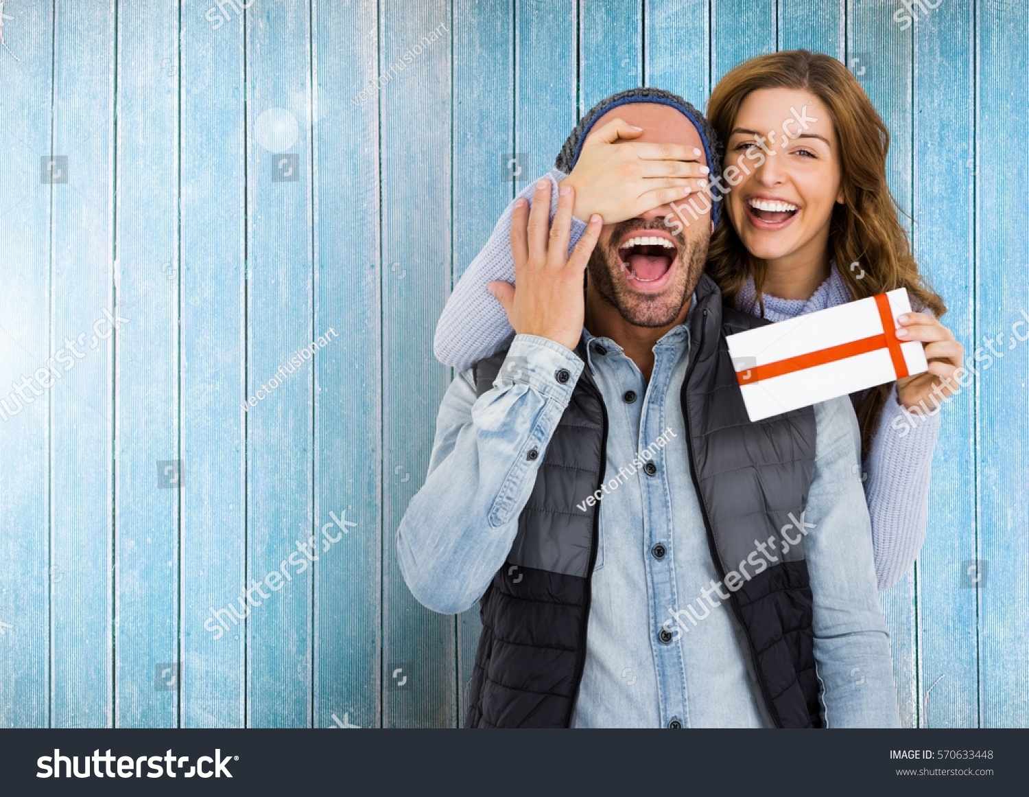 Woman giving surprise gift to man against wooden background #570633448
