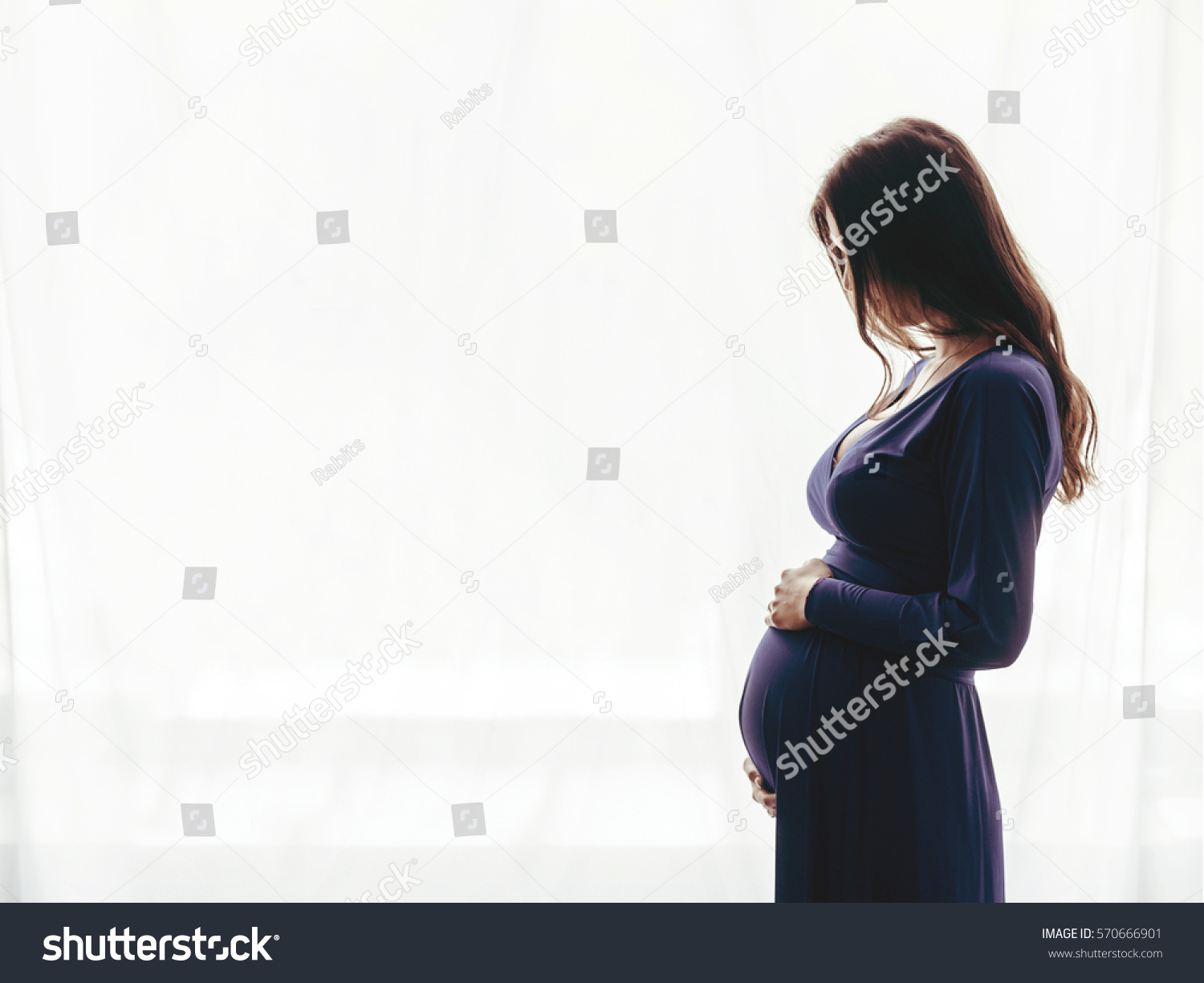 Pregnant woman standing against the window #570666901