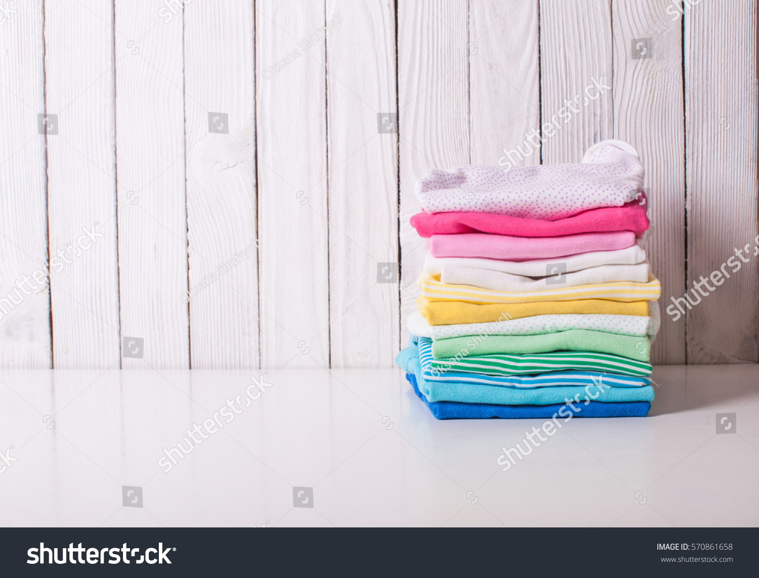Colorful baby clothes of folded pile on a white background #570861658
