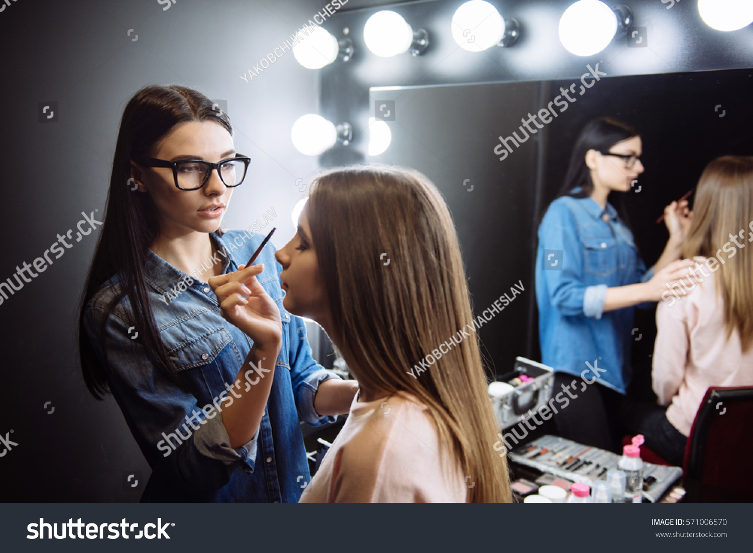 Nice attractive makeup artist using a cosmetic brush #571006570