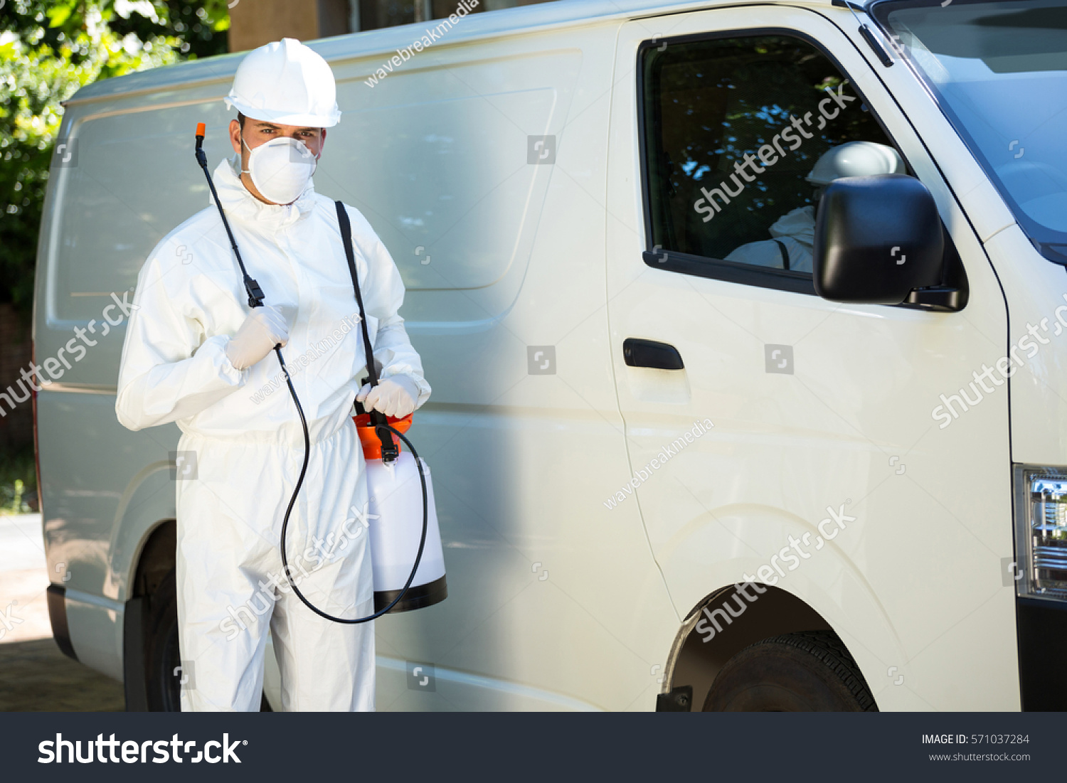 Portrait of pest control man standing next to a van on a street #571037284