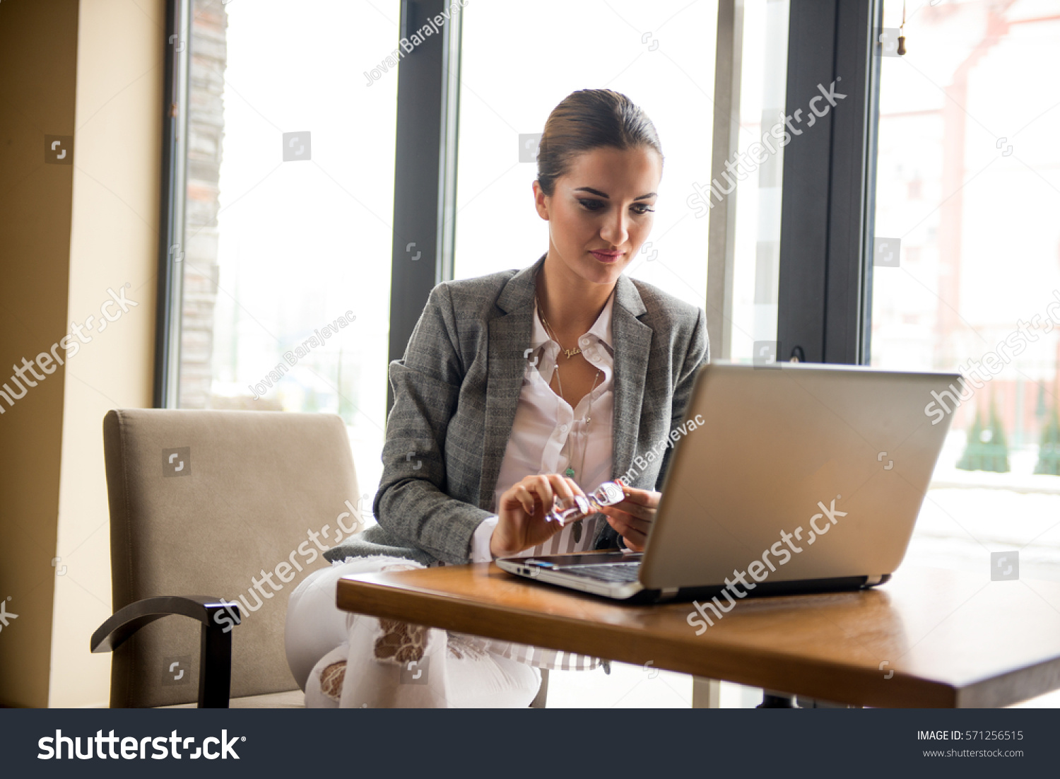 Bussineswoman with a glasses is working on computer, in a restaurant #571256515