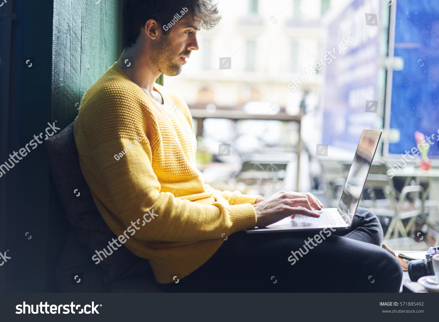 Stylish male freelancer working on new startup project making internet researchers analyzing data using laptop computer and wireless connection to 4G internet in city cafe with free wireless zone #571885492