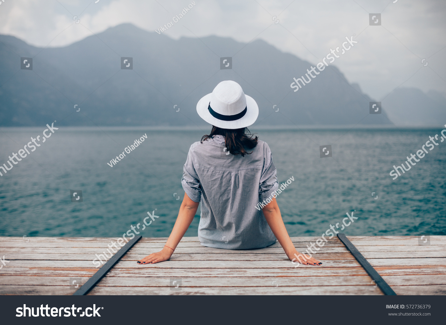Beautiful woman relaxing on pier in Garda Lake. Vacation concept #572736379