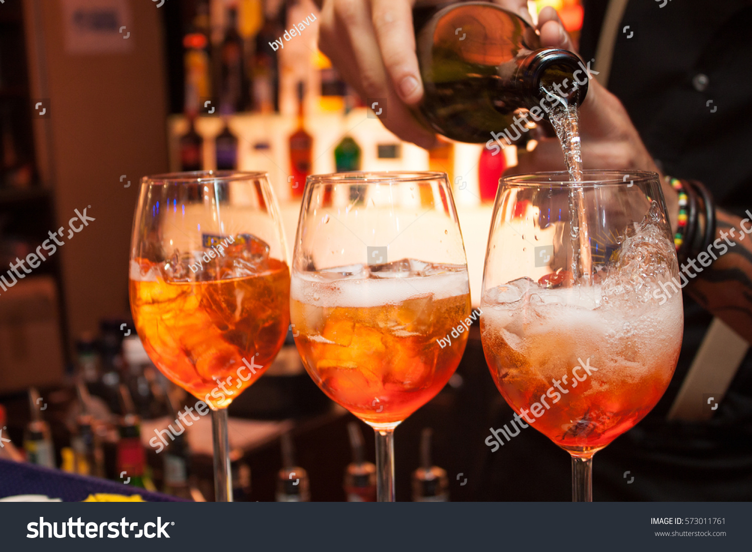 three glasses of cocktails on the bar. bartender pours a glass of sparkling wine with Aperol. #573011761