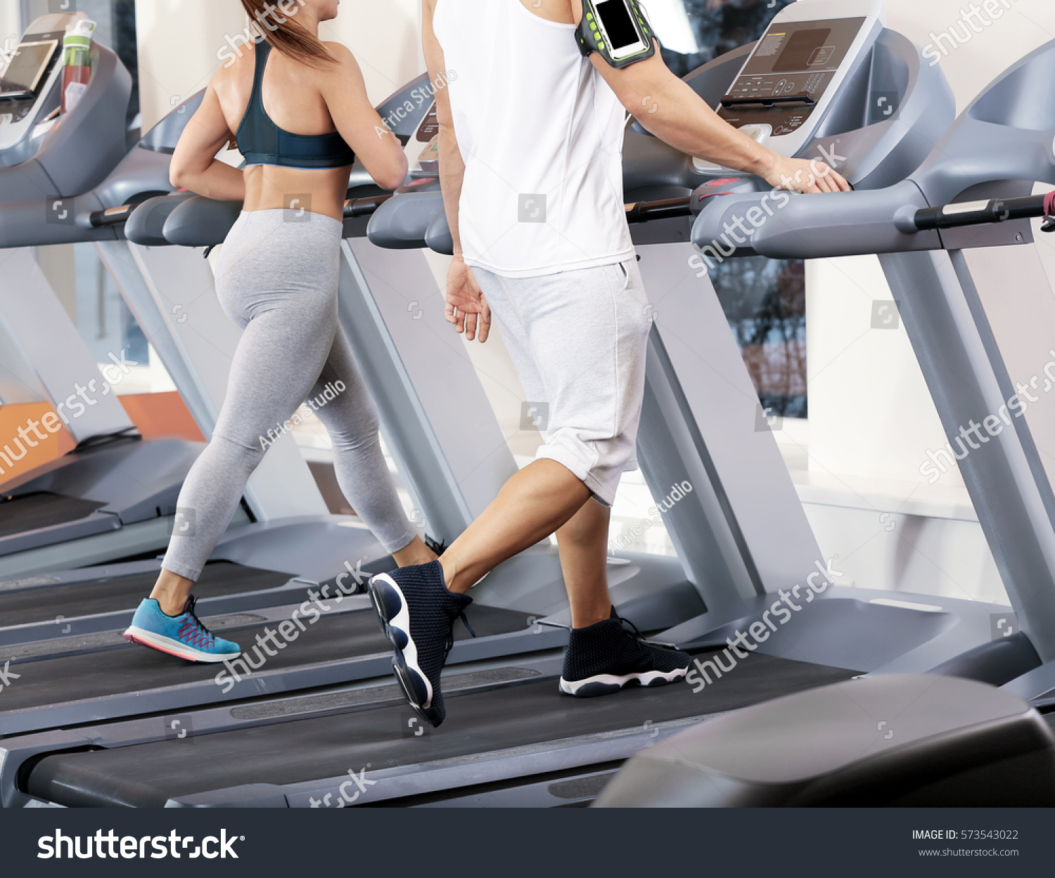 Young people running on treadmills in gym #573543022