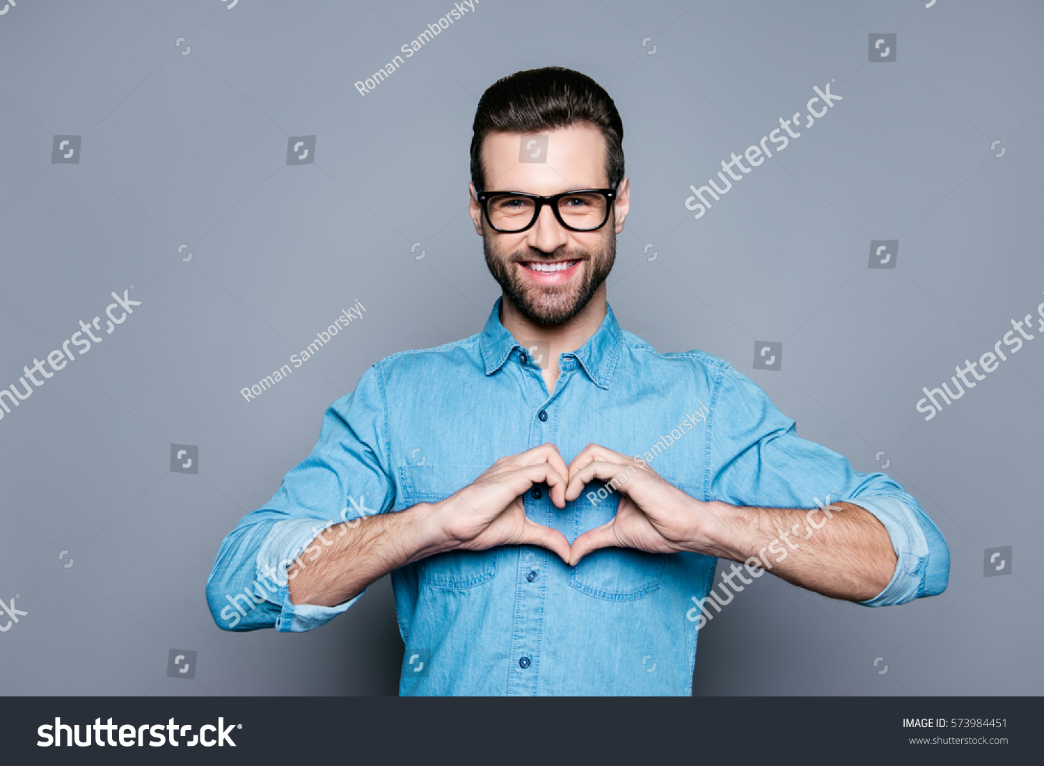Portrait of happy handsome man in glasses making heart with fingers. #573984451