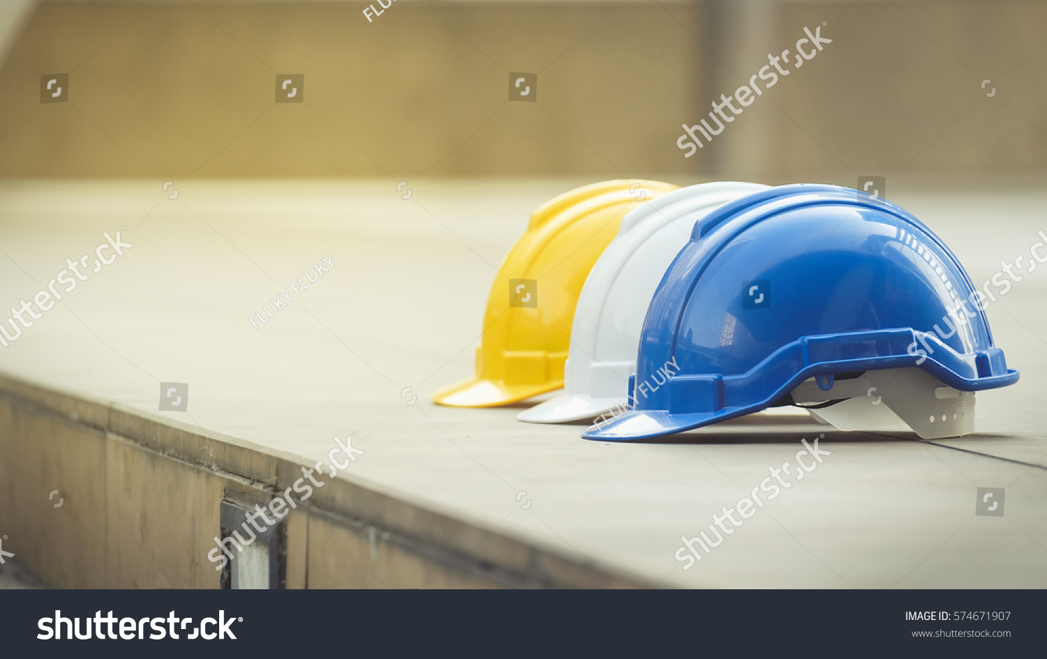 white, yellow and blue hard safety helmet hat for safety project of workman as engineer or worker, on concrete floor on city #574671907