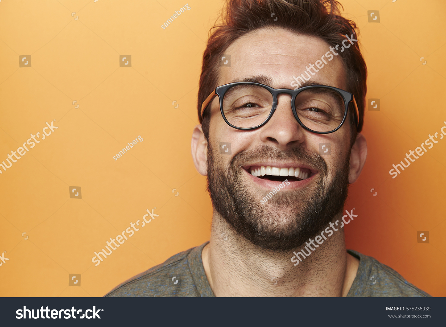 Man laughing in orange studio, close up #575236939