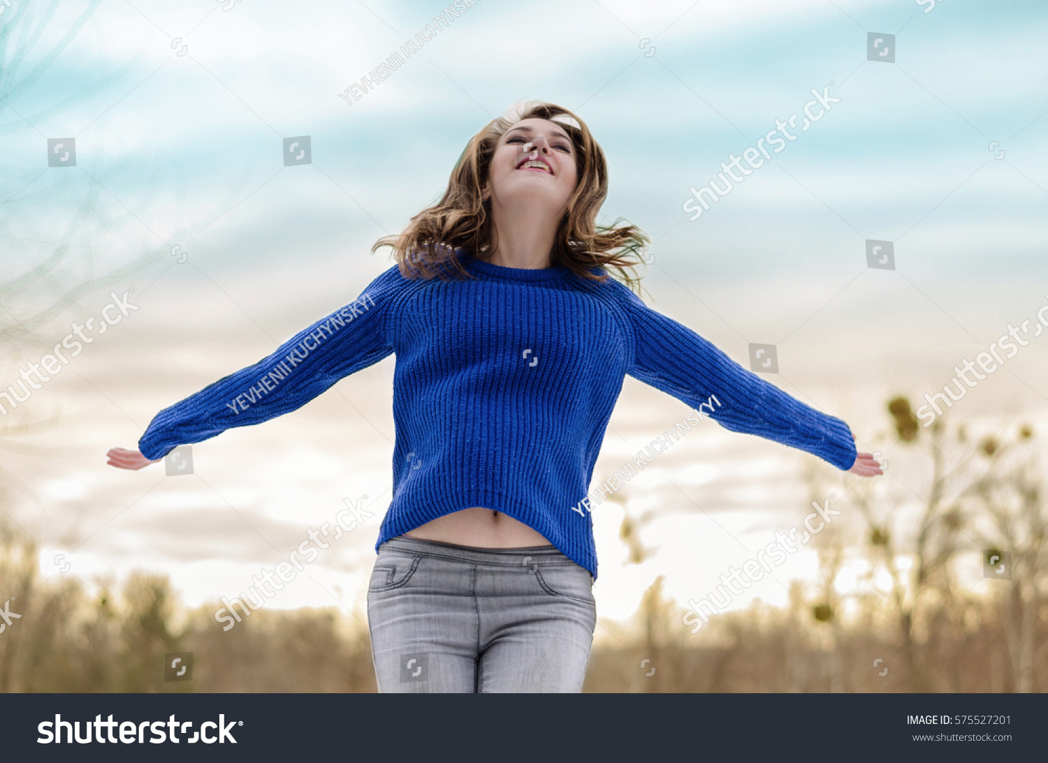 Happy, Smiling Girl in the Forest Positive Attitude and Happiness Spreads His Hands Against the Background of a Beautiful and Colourful Sky #575527201