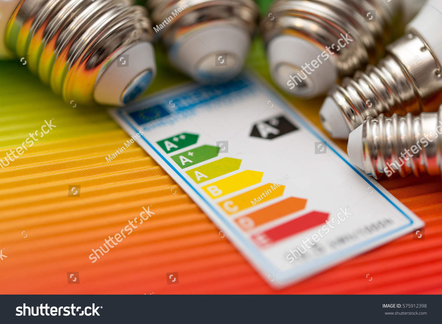 detail of bulb´s screw-threads with energy scale table on colorful background #575912398