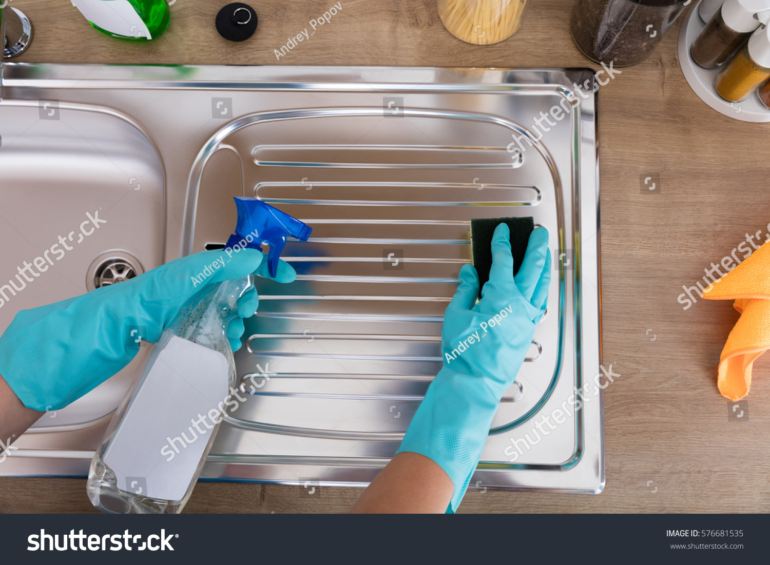 High Angle View Of Person Hands Cleaning Kitchen Sink With Spray Bottle And Sponge #576681535