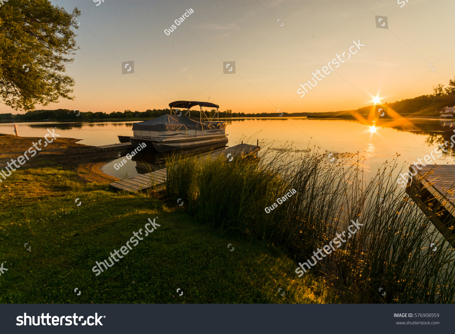 View of lake sunrise showing docked pontoon boat #576908959