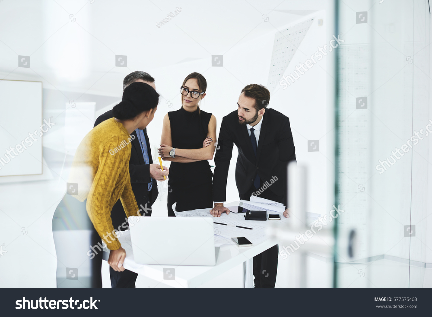 Crew of skilled marketing experts consulting with executive about rebranding of corporation suggesting new advertising campaign to change style sharing opinions on formal meeting in conference hall #577575403