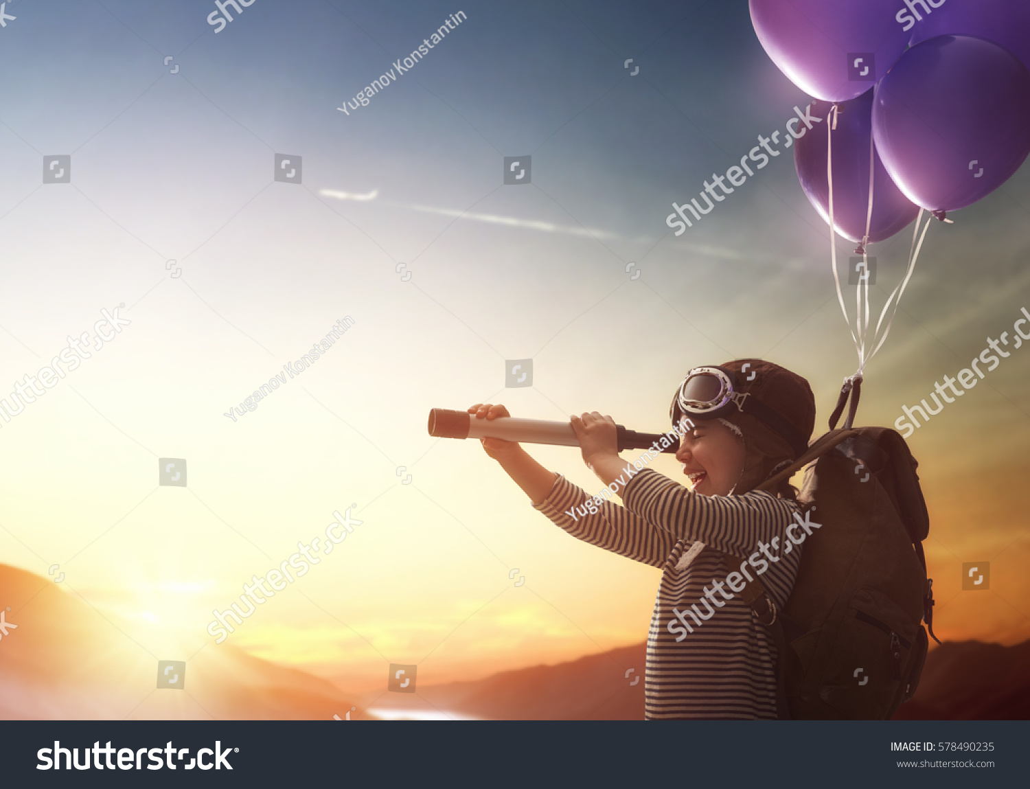 Dreams of travel! Child flying on balloons against the backdrop of a sunset. #578490235