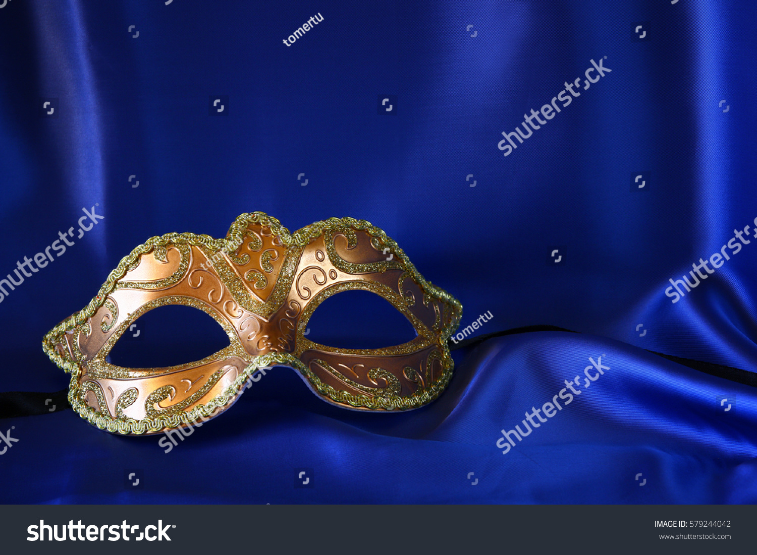 Image of elegant gold venetian mask on blue silk background #579244042