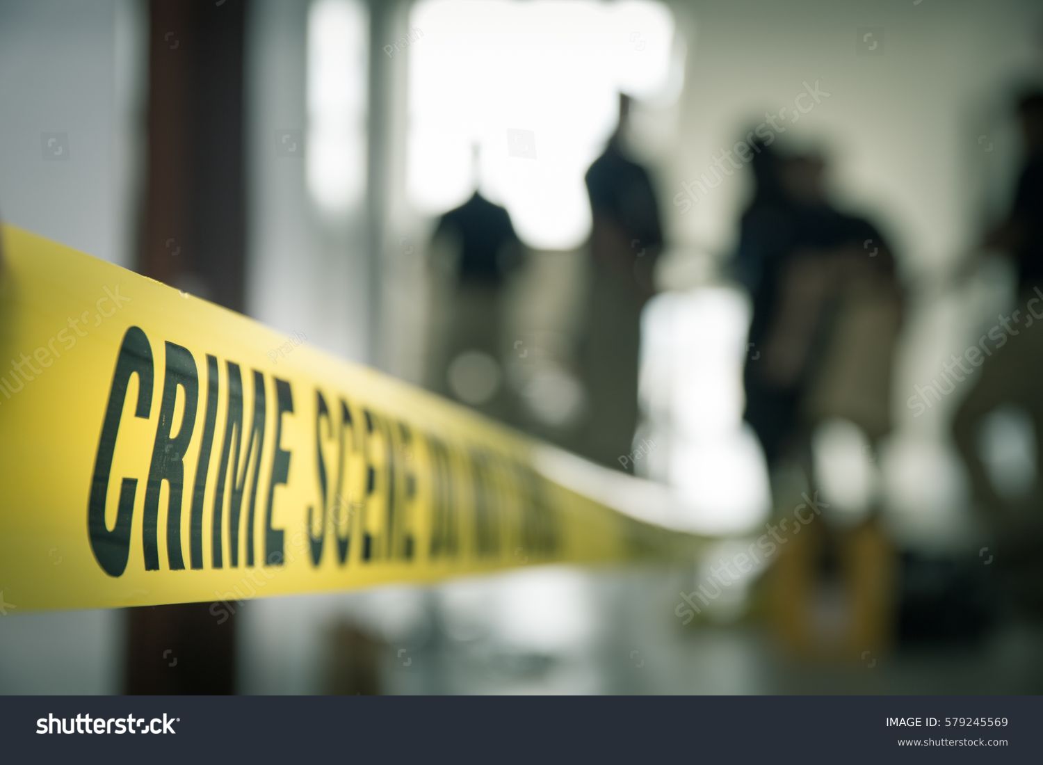 crime scene tape with blurred forensic law enforcement background in cinematic tone and copy space #579245569