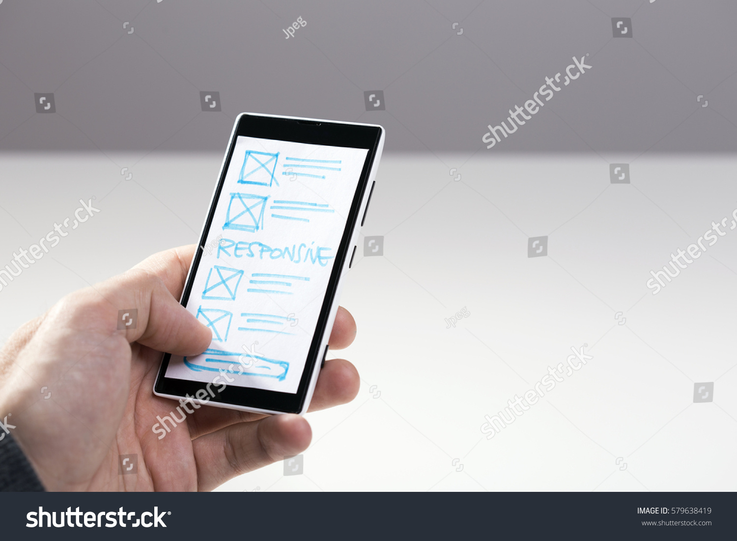 Designer hand holding smart phone with paper sketch for mobile responsive website #579638419